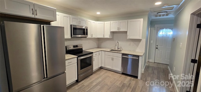 kitchen featuring sink, light hardwood / wood-style flooring, light stone countertops, appliances with stainless steel finishes, and white cabinetry