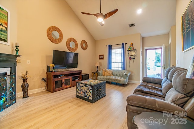 living room featuring ceiling fan, a fireplace, high vaulted ceiling, and light hardwood / wood-style floors