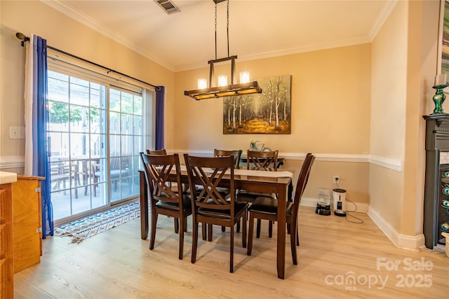 dining space with crown molding, light hardwood / wood-style flooring, and a chandelier