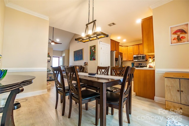 dining area featuring crown molding, light hardwood / wood-style flooring, and vaulted ceiling