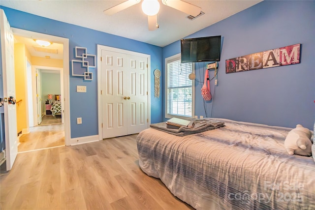 bedroom with a closet, light hardwood / wood-style floors, ceiling fan, and lofted ceiling