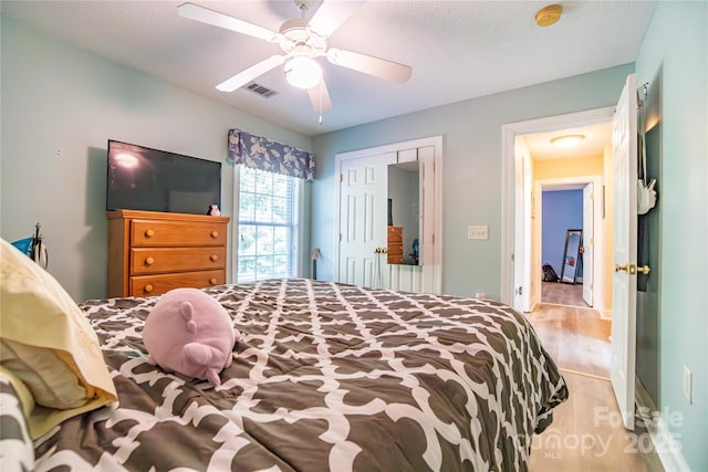 bedroom featuring ceiling fan, light hardwood / wood-style flooring, and a closet