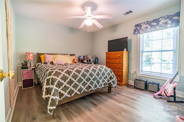 bedroom with hardwood / wood-style flooring, ceiling fan, and multiple windows