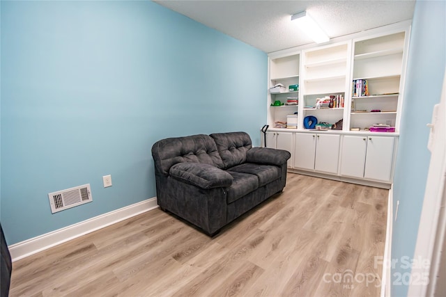 living area featuring light hardwood / wood-style floors and a textured ceiling