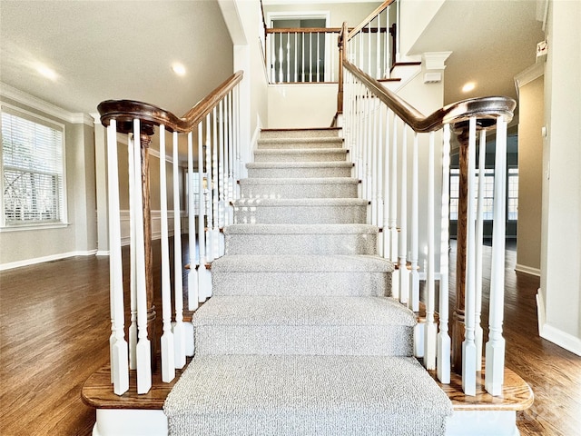 stairway with wood-type flooring and crown molding