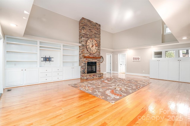 unfurnished living room featuring a towering ceiling, a fireplace, and light hardwood / wood-style flooring