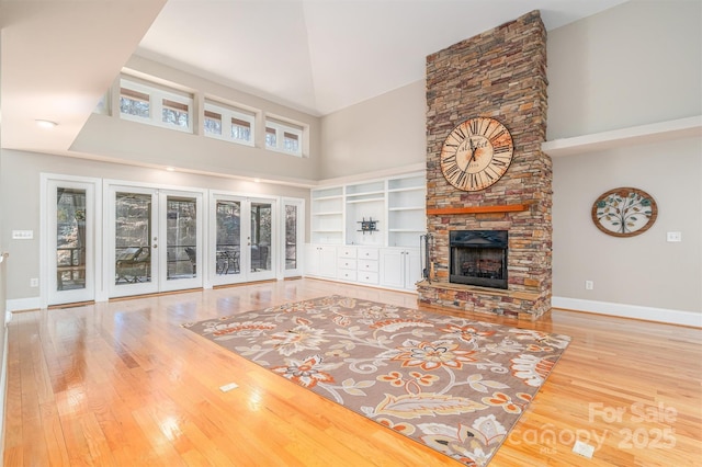 unfurnished living room with a fireplace, wood-type flooring, a towering ceiling, and a healthy amount of sunlight