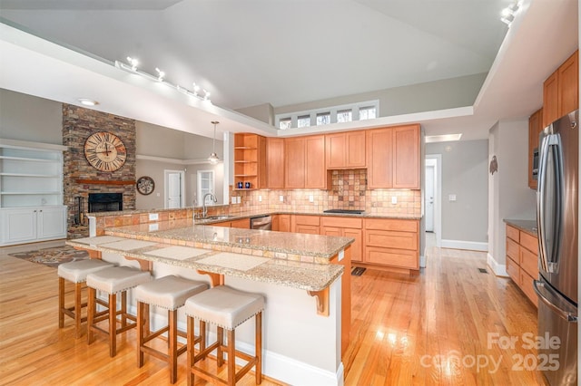 kitchen featuring kitchen peninsula, a breakfast bar, stainless steel appliances, and a fireplace