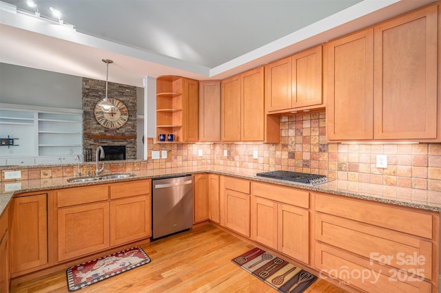 kitchen featuring light stone countertops, sink, stainless steel appliances, pendant lighting, and light wood-type flooring