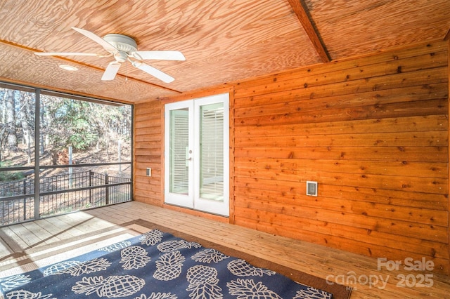 unfurnished sunroom with ceiling fan, a healthy amount of sunlight, and wood ceiling