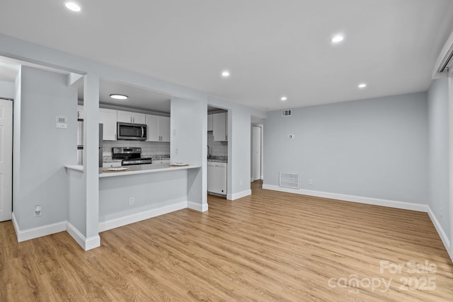 kitchen with white cabinets, tasteful backsplash, kitchen peninsula, a breakfast bar area, and appliances with stainless steel finishes