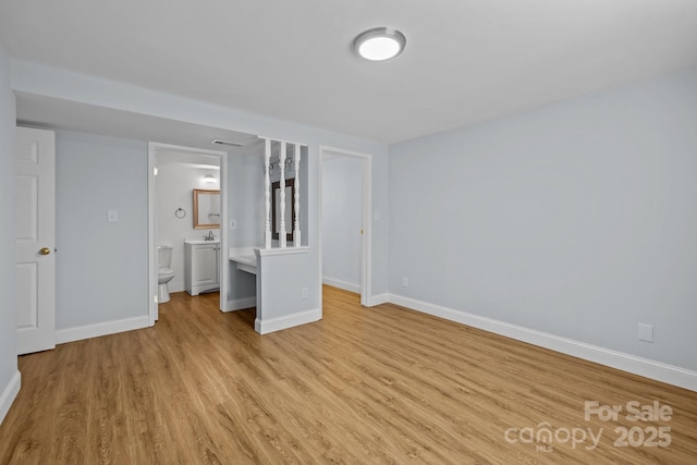 unfurnished bedroom featuring light wood-type flooring and ensuite bath