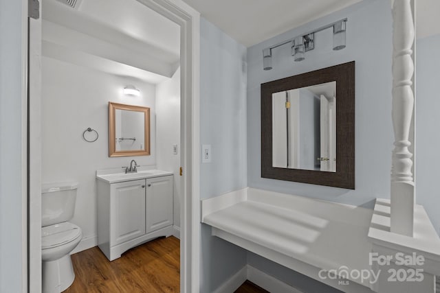 bathroom featuring toilet, vanity, and hardwood / wood-style floors