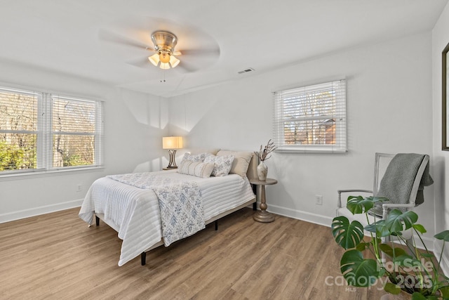 bedroom with hardwood / wood-style flooring, ceiling fan, and multiple windows