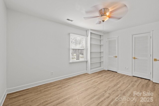 unfurnished bedroom with multiple closets, ceiling fan, and light hardwood / wood-style flooring