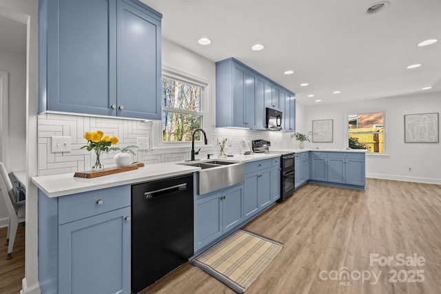 kitchen with sink, blue cabinets, plenty of natural light, decorative backsplash, and black appliances