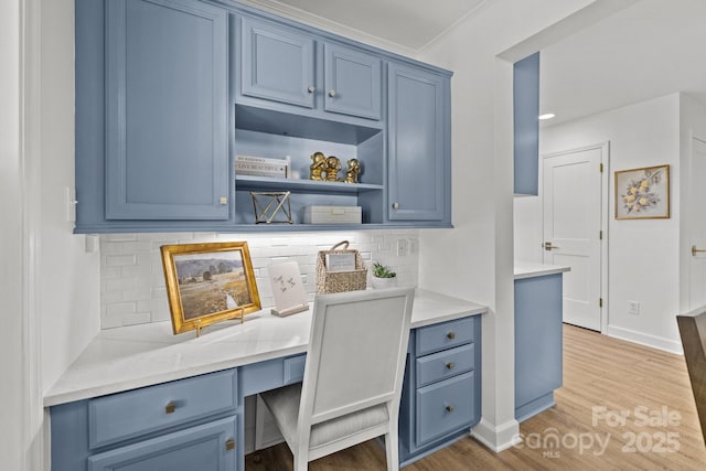 home office featuring light wood-type flooring, built in desk, and ornamental molding