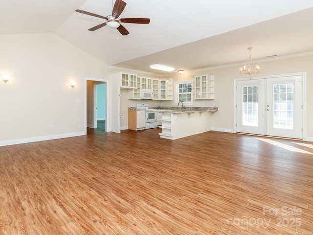 unfurnished living room with french doors, light hardwood / wood-style flooring, crown molding, vaulted ceiling, and ceiling fan with notable chandelier