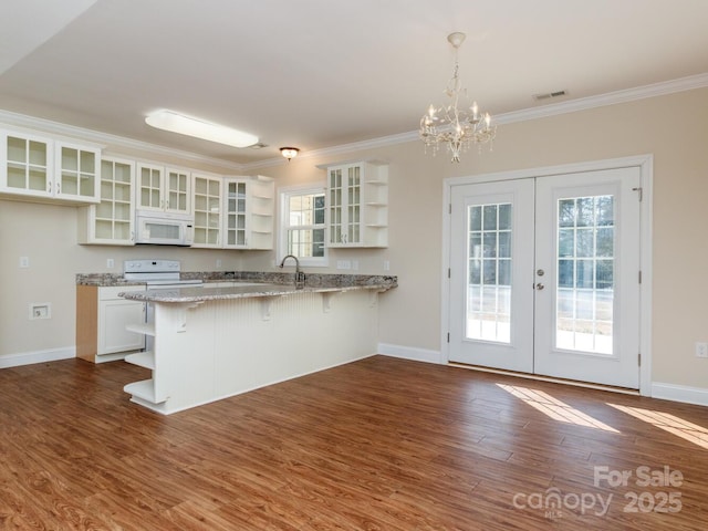 kitchen featuring a breakfast bar, white appliances, french doors, white cabinets, and hanging light fixtures