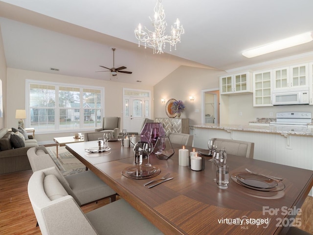 dining room featuring ceiling fan with notable chandelier, lofted ceiling, and light hardwood / wood-style flooring