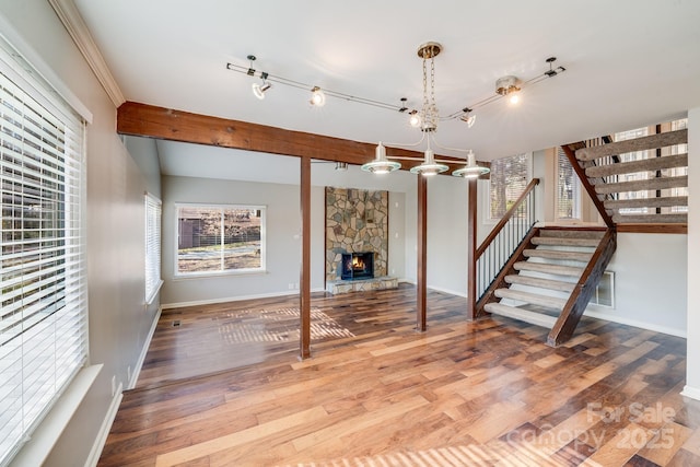 unfurnished living room featuring a chandelier, hardwood / wood-style flooring, and a stone fireplace