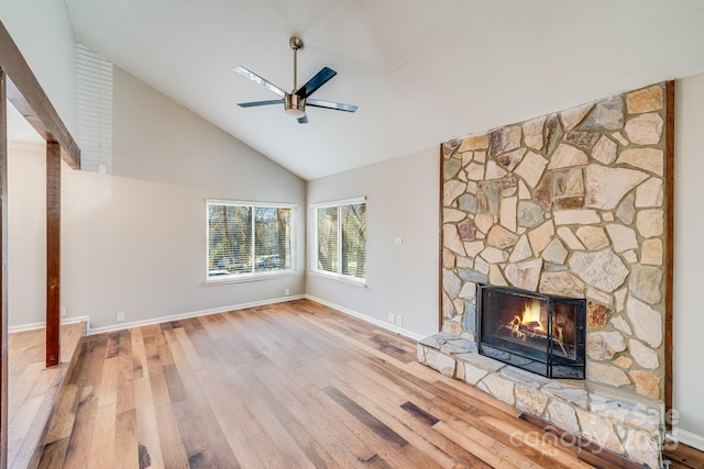 unfurnished living room with ceiling fan, a stone fireplace, high vaulted ceiling, and hardwood / wood-style flooring