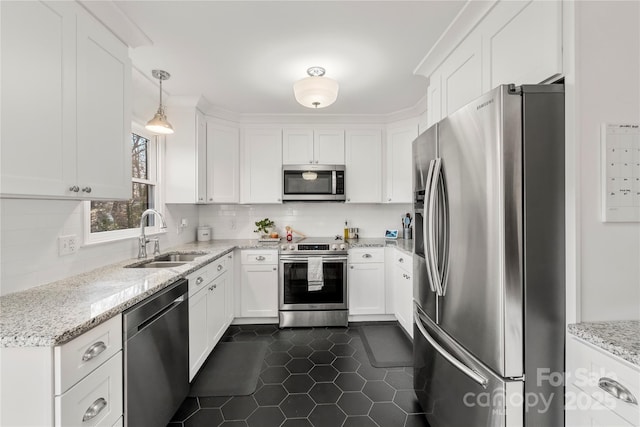 kitchen featuring appliances with stainless steel finishes, light stone counters, sink, white cabinets, and hanging light fixtures