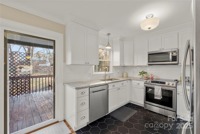 kitchen featuring sink, stainless steel appliances, light stone counters, pendant lighting, and white cabinets