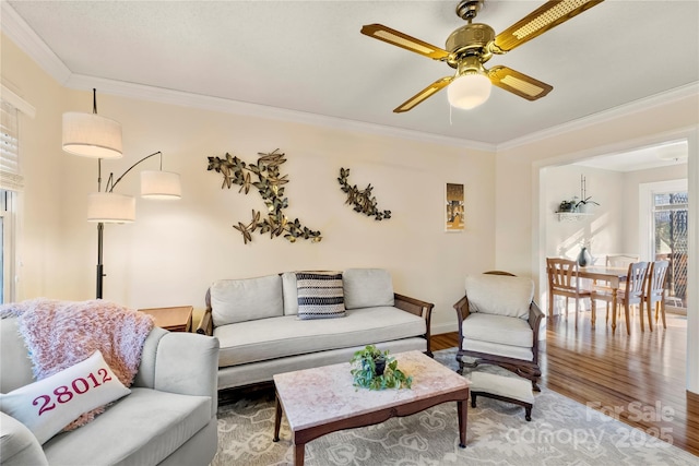 living room featuring wood-type flooring, ceiling fan, and crown molding