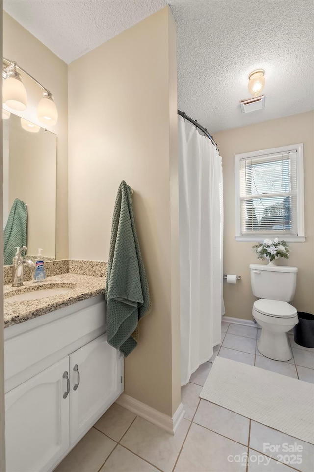 bathroom with toilet, a textured ceiling, vanity, and tile patterned floors