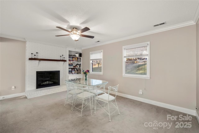 unfurnished dining area with ceiling fan, ornamental molding, a fireplace, and light carpet