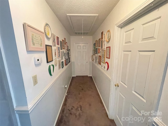 hall featuring carpet floors and a textured ceiling