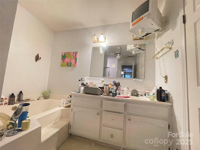 bathroom featuring a bathtub, vanity, a textured ceiling, ceiling fan, and tile patterned flooring