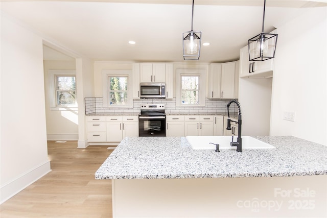 kitchen featuring kitchen peninsula, white cabinets, hanging light fixtures, and appliances with stainless steel finishes