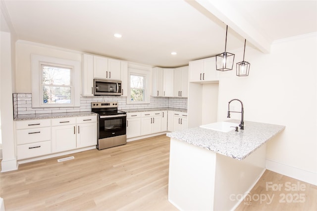 kitchen featuring appliances with stainless steel finishes, pendant lighting, white cabinets, and sink