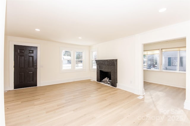 living room featuring light wood-type flooring, ornamental molding, and a fireplace