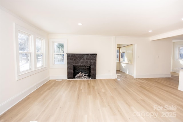 unfurnished living room featuring a brick fireplace, light hardwood / wood-style floors, and ornamental molding