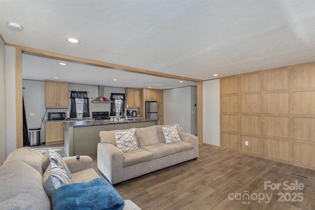 living room featuring wood-type flooring, a textured ceiling, and wooden walls