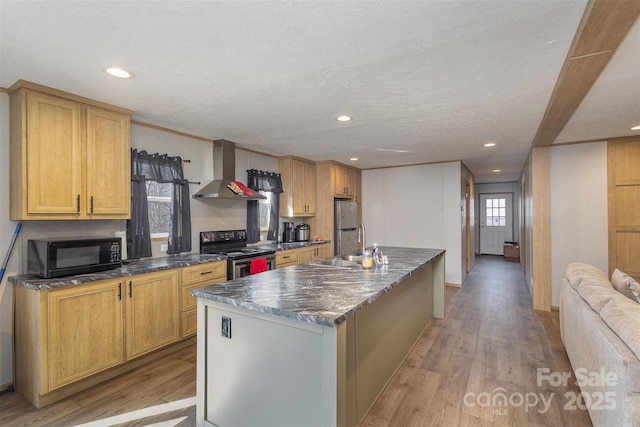 kitchen with a textured ceiling, light wood-type flooring, electric range, a center island with sink, and wall chimney exhaust hood