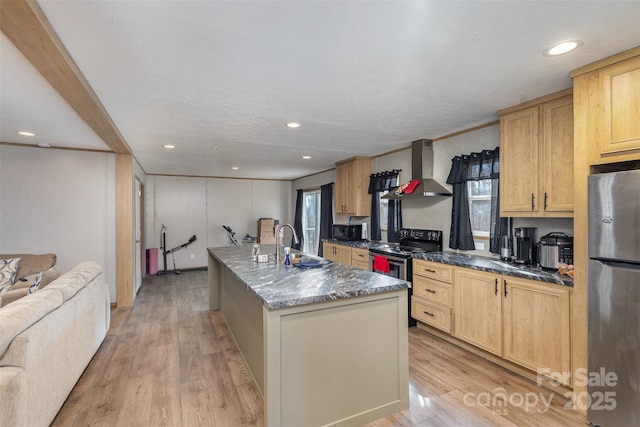 kitchen featuring electric range oven, wall chimney exhaust hood, light hardwood / wood-style flooring, stainless steel fridge, and a center island with sink