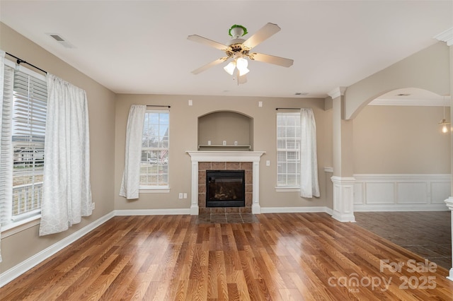 unfurnished living room featuring ceiling fan, wood-type flooring, and a tiled fireplace