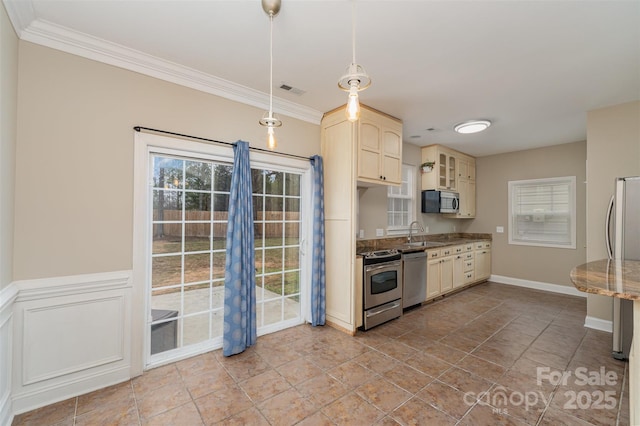 kitchen featuring pendant lighting, cream cabinetry, stainless steel appliances, and sink