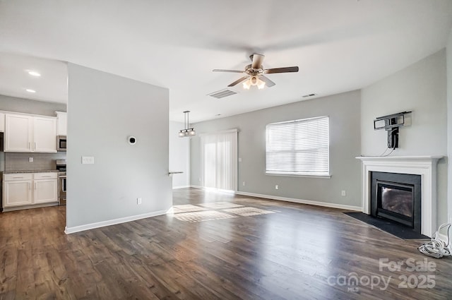 unfurnished living room featuring ceiling fan and dark hardwood / wood-style flooring