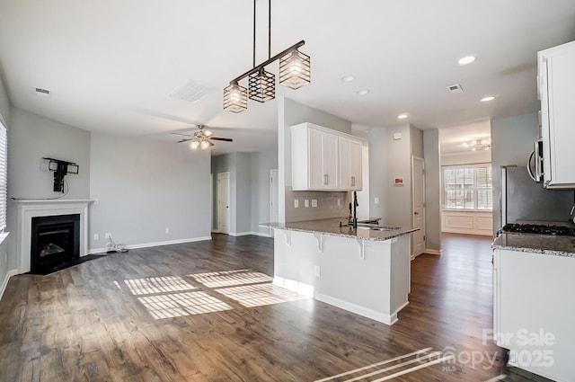 kitchen featuring stone counters, white cabinetry, tasteful backsplash, kitchen peninsula, and a breakfast bar area