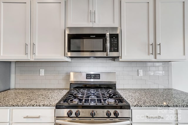 kitchen with decorative backsplash, stainless steel appliances, white cabinets, and light stone countertops