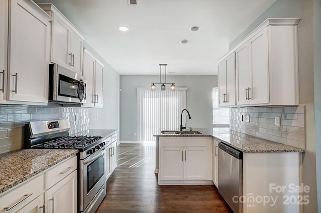 kitchen featuring light stone countertops, stainless steel appliances, sink, decorative light fixtures, and white cabinets