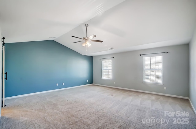 spare room with ceiling fan, light carpet, and vaulted ceiling