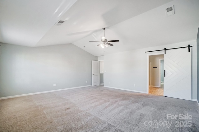 interior space featuring a barn door, vaulted ceiling, and ceiling fan