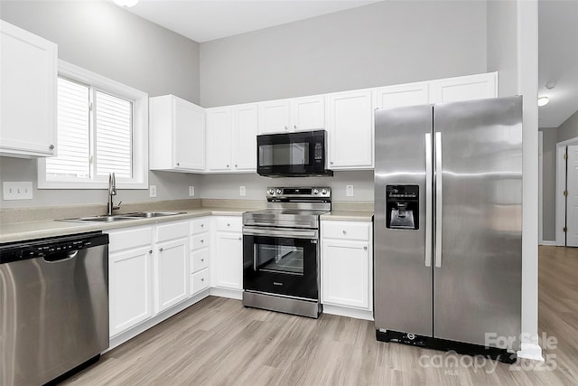 kitchen featuring white cabinetry, sink, stainless steel appliances, and light wood-type flooring