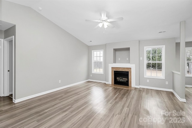 unfurnished living room featuring ceiling fan, lofted ceiling, a premium fireplace, and light wood-type flooring